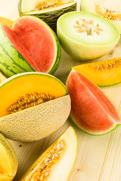 Photo variety of organic melons sliced on wood table.