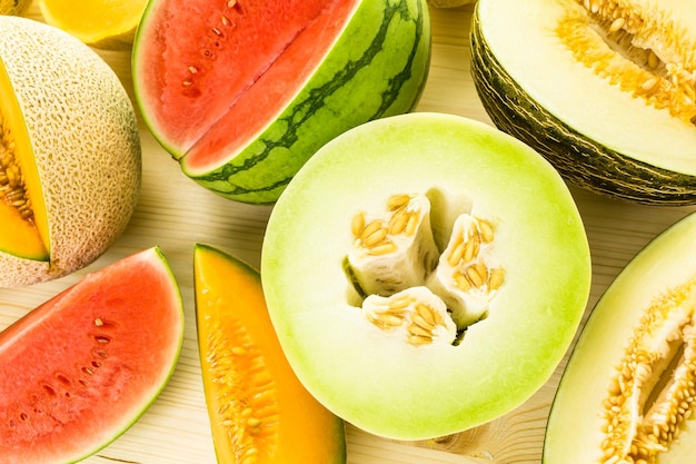 Variety of organic melons sliced on wood table.