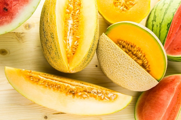 Variety of organic melons sliced on wood table.