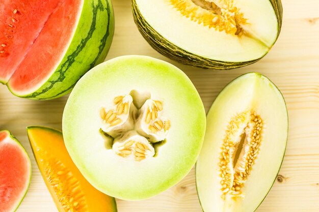 Variety of organic melons sliced on wood table.