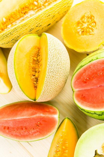 Photo variety of organic melons sliced on wood table.