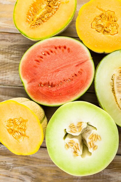 Variety of organic melons sliced on wood table.