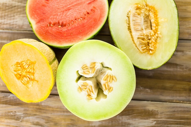 Variety of organic melons sliced on wood table.