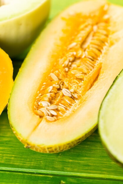 Variety of organic melons sliced on wood table.