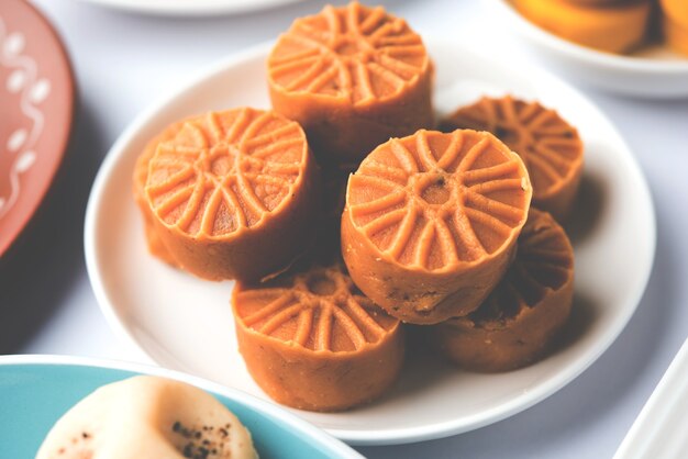 Variety of Peda or Pedha Served in a bowl or plate over white background or with pile of gifts. It's a popular festival food from India. selective focus