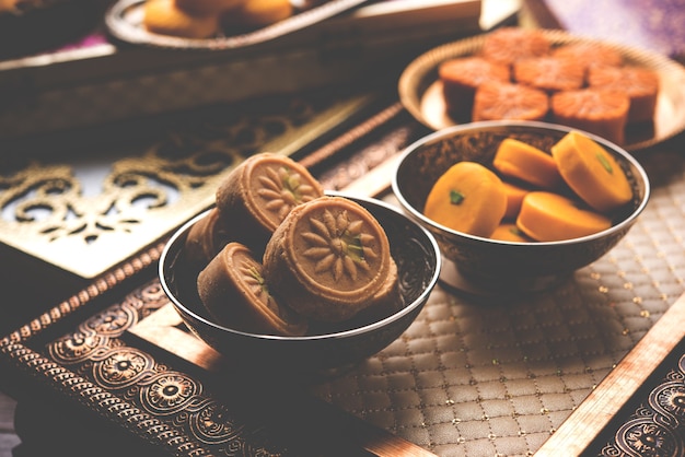 Variety of Peda or Pedha Served in a bowl or plate over white background or with pile of gifts. It's a popular festival food from India. selective focus