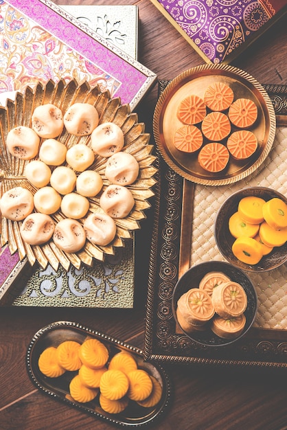 Foto varietà di peda o pedha servita in una ciotola o un piatto su sfondo bianco o con un mucchio di regali. è un cibo da festival popolare dall'india. messa a fuoco selettiva