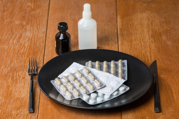 Variety of pills on plate with fork and knife