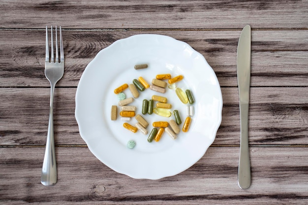 A variety of pills and supplements on a plate with a knife and fork