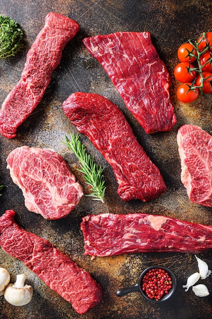 Variety,  of raw beef steaks  flap flank Steak, machete steak or skirt cut, Top blade or flat iron beef and tri tip, triangle roast with denver cut top view over old rustic metal surface .