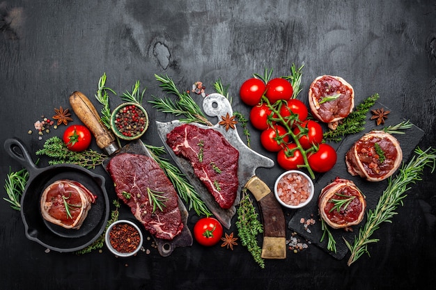 Variety of raw black angus prime meat steaks beef rump steak,\
tenderloin fillet mignon for grilling on old meat cleaver on dark\
background. banner, menu recipe top view.