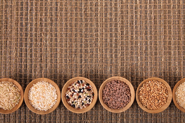 Variety of rice and grains in bowls on bamboo mat