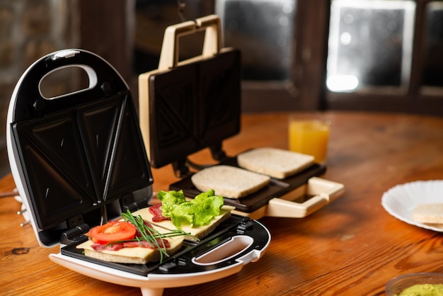 A variety of sandwiches that can be prepared in a sandwich maker concept Row of electric sandwich makers on a wooden background