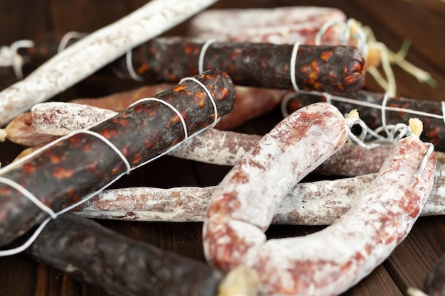 Foto una varietà di prodotti a base di salsiccia in primo piano su uno sfondo di legno marrone