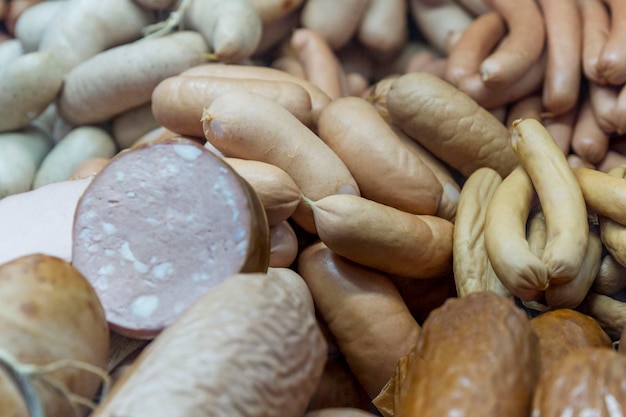 A variety of sausages on the counter in the store Smoked sausages of different sizes and shapes Closeup