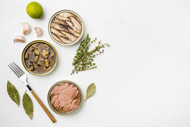 Photo variety of seafood tuna mussel fish tin cans set, on white stone table background, top view flat lay, with copy space for text