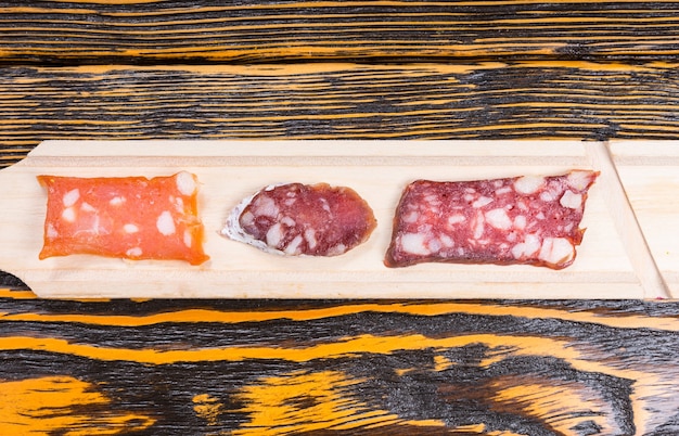 Variety of Sliced Smoked Gourmet Cured Meats on Long Board on Rustic Wooden Table with Wood Grain and Copy Space