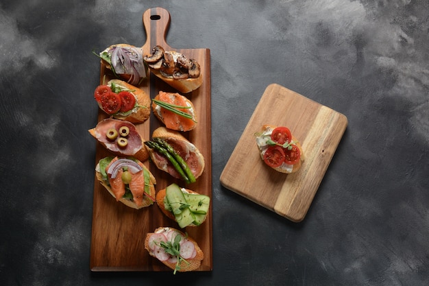 Variety of small sandwiches on wooden board