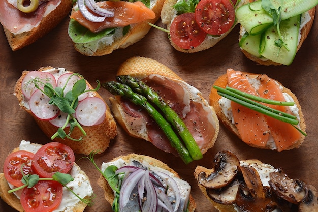 Variety of small sandwiches on wooden board