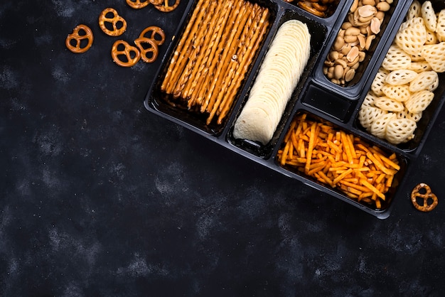 Photo a variety of snacks on the box for beer on a concrete black table