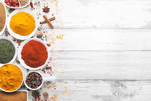 Variety of spices in bowls on white wooden background