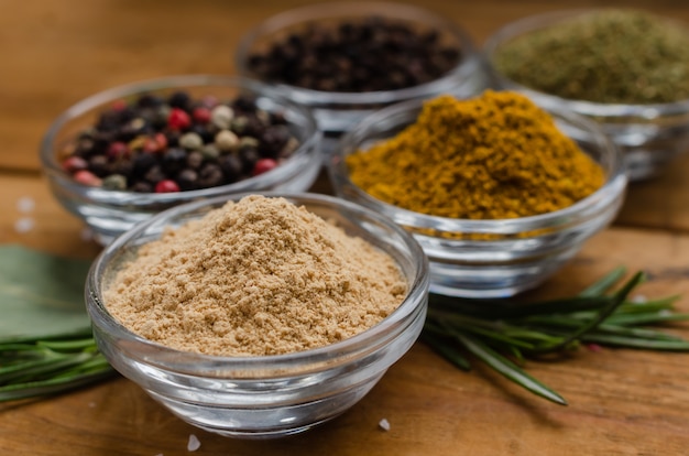 Variety of spices in round glass bowls. ground ginger, hops-suneli, kari, black pepper and a mixture.