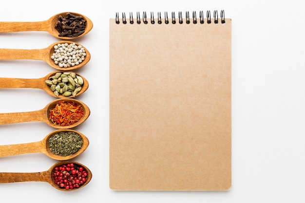 Variety of spices in wooden spoons and notebook