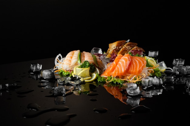 A variety of sushi with pieces of melting ice on a black background with reflection