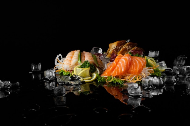 A variety of sushi with pieces of melting ice on a black background with reflection