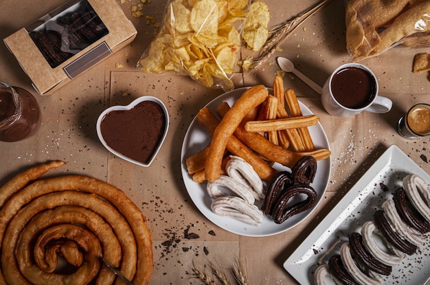 Variety of traditional churros with granulated sugar and chocolate on a craf paper table. Top view. Typical churreria products