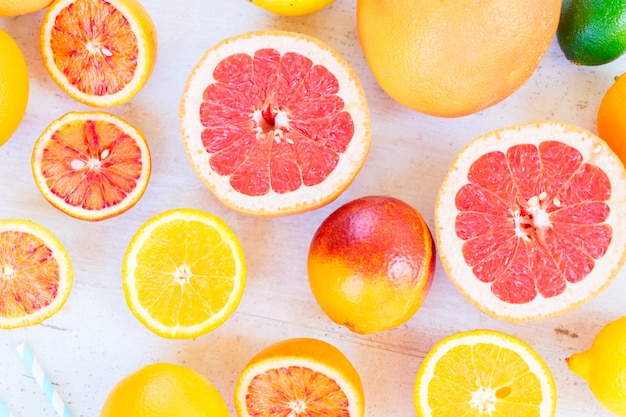 Photo variety of whole an cut citruses on white wooden table