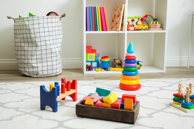 Variety of wooden and plastic educating toys left on a white carpet after children's games Daycare or kindergarten room with toys