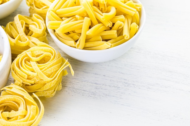 Variety of yellow dry pasta in small round bowls.