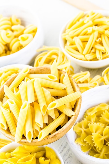 Variety of yellow dry pasta in small round bowls.