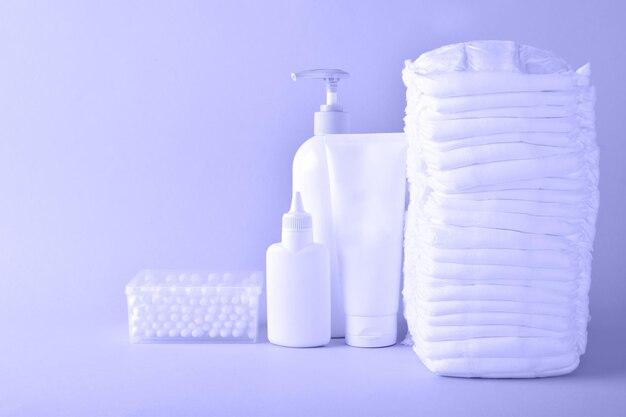 Various accessories for children's hygiene. A large stack of diapers next to them are bottles of baby cosmetics. Copy space