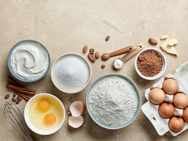 Various baking ingredients on beige color table background, top view