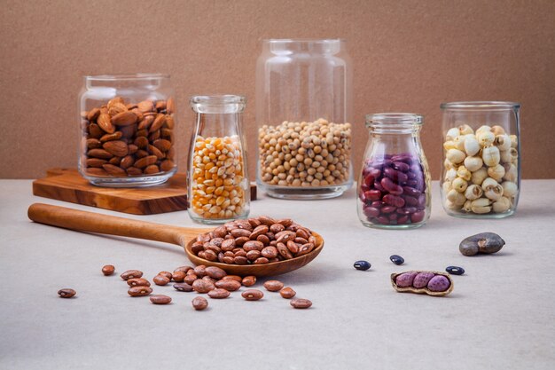 Various beans and nuts in the glass on brown background. 