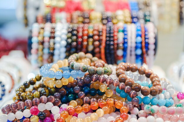 Various beautiful gem bracelets stacked together for sale in the market.