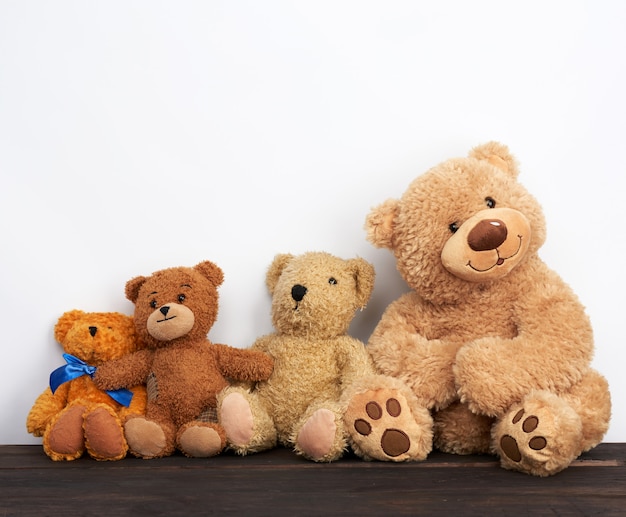 Various brown teddy bears are sitting on a brown wooden table