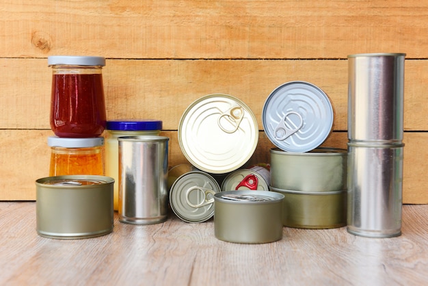 Vari alimenti in scatola in lattine di metallo sul tavolo di legno - prodotti in scatola non deperibili per la conservazione degli alimenti in cucina o per donazioni