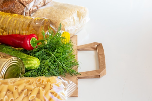 Various canned food, pasta and cereals in a cardboard box. food\
donations or food delivery concept.