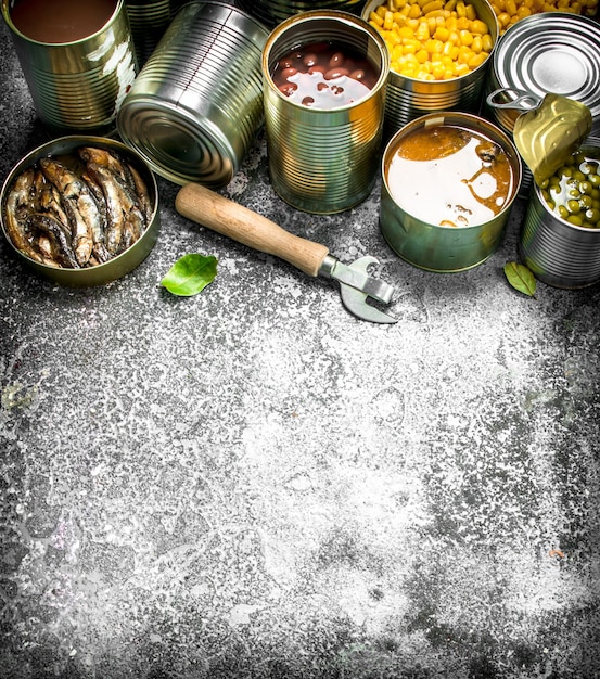 Various canned foods with meat, fish, vegetables and fruits in tin cans. On a rustic background.