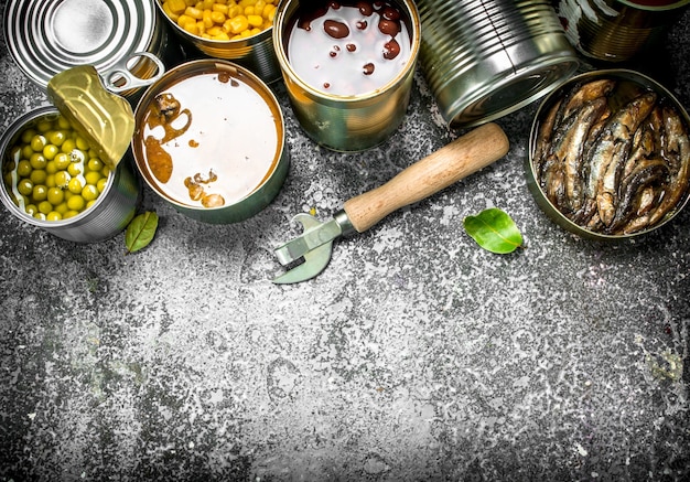 Various canned foods with meat, fish, vegetables and fruits in tin cans. On a rustic background.