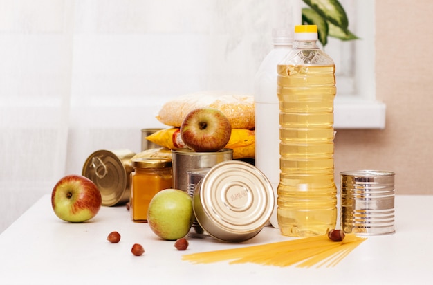 Various canned goods, pasta and cereals on a white table. food\
donation or food delivery concept.