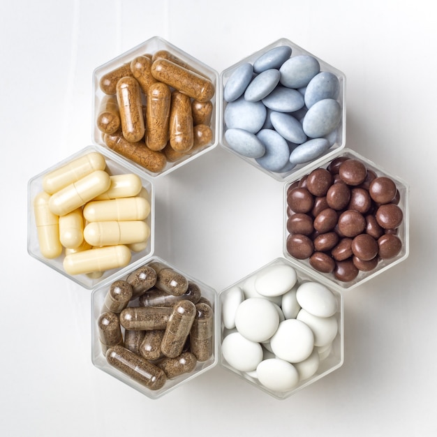 Various capsules and pills with dietary supplements or medicines in hexagonal jars are in the form of a honeycomb