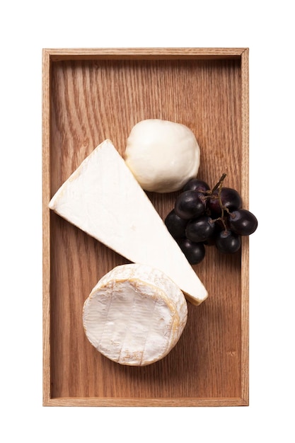 Various cheese and grapes on wooden plate isolated on background