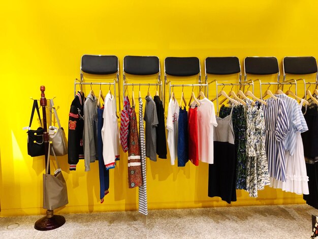 Various clothes hanging on rack against yellow wall