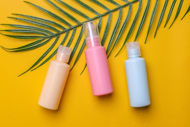 Various color of plastic bottles with no label for beauty products on a yellow background