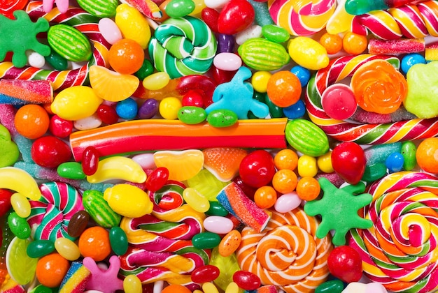 Various colorful candies, jellies, lollipops and marmalade as background, top view