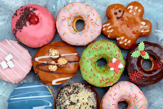 Various colorful donuts on blue surface. Top view.